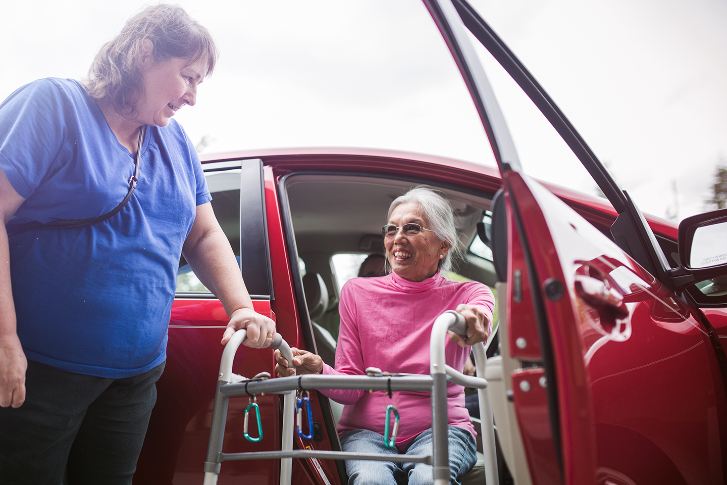 a nurse helps an older woman get out of a car